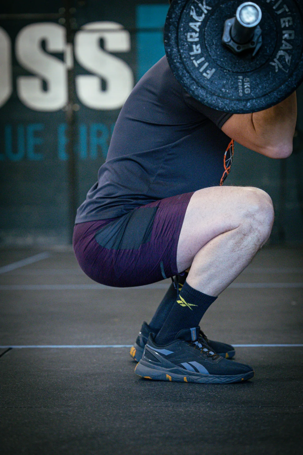Athlète en squat profond avec une barre chargée à la box CrossFit Blue Bird