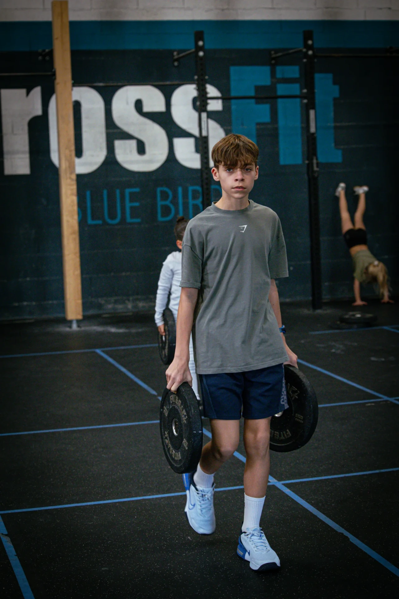 Ado en farmer carry devant le mur CrossFit Blue Bird