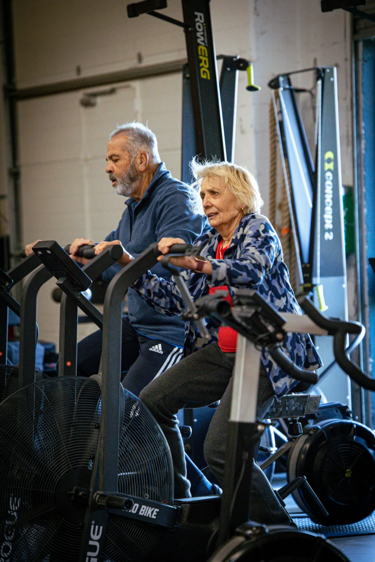 Deux adhérents seniors côte à côte sur les Assault Bike pendant le cours CrossFit senior