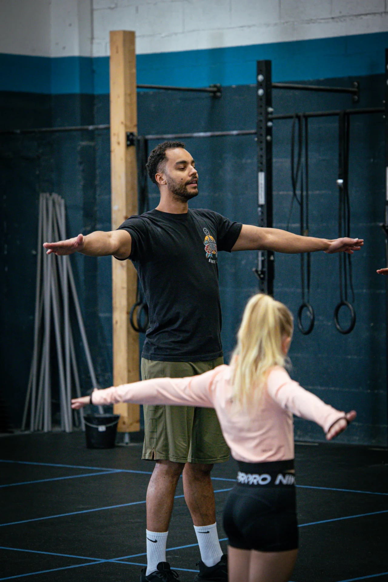 Coach guidant une enfant pendant l'échauffement du cours CrossFit Kids
