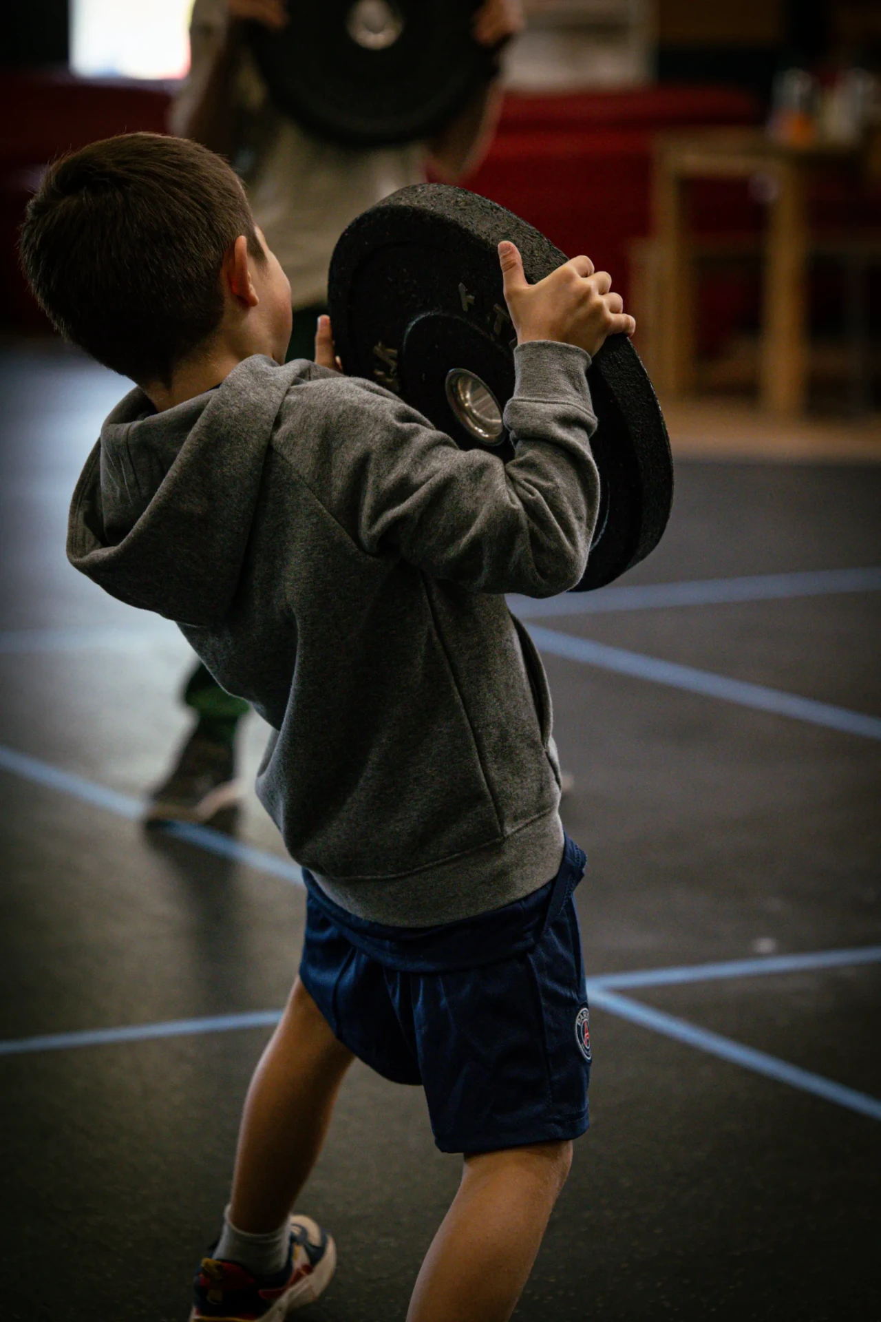 Enfant portant un disque pendant un cours de CrossFit pour enfant à Saint-Étienne