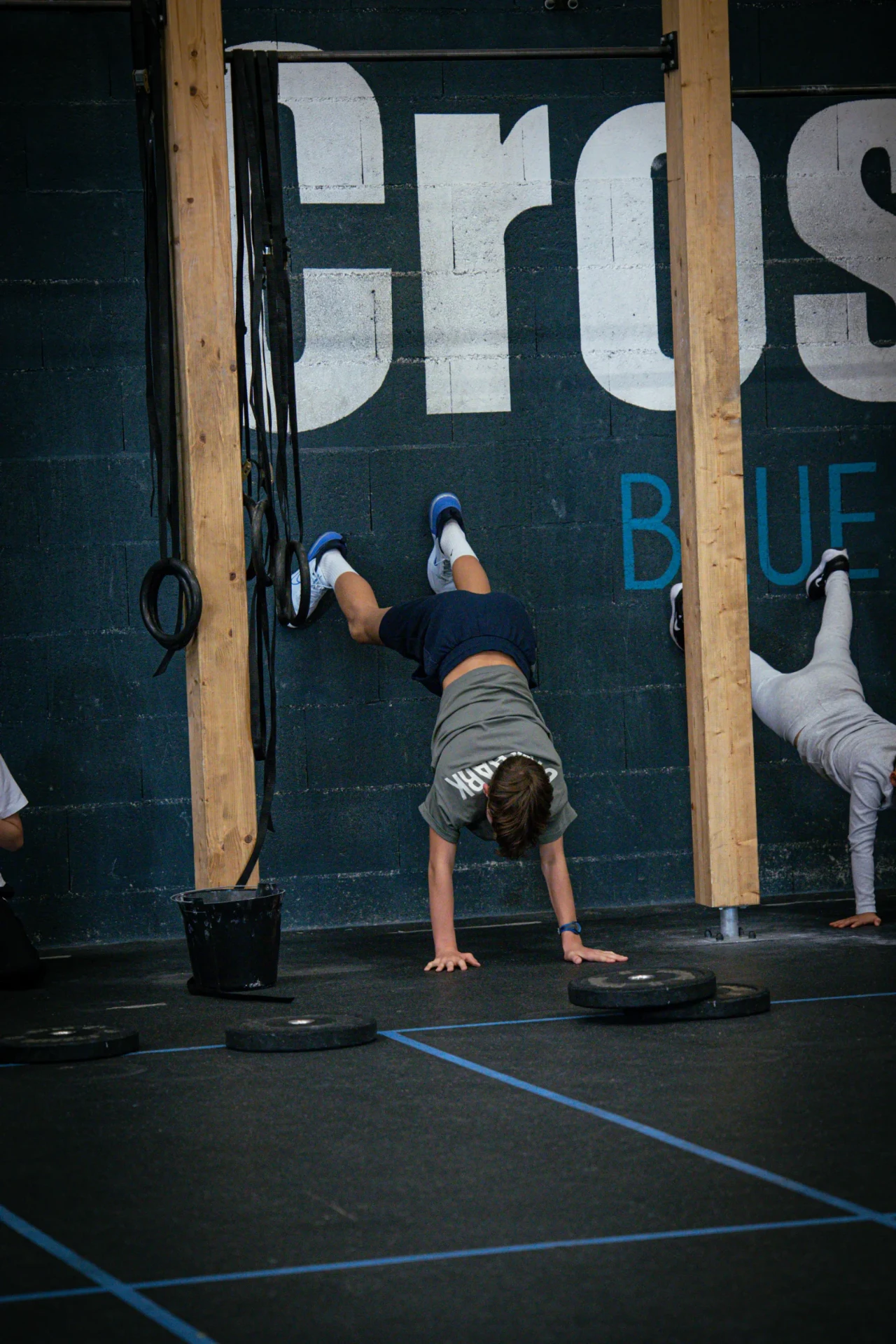 Enfant en handstand contre le mur pendant l'atelier gymnastique du cours Kids