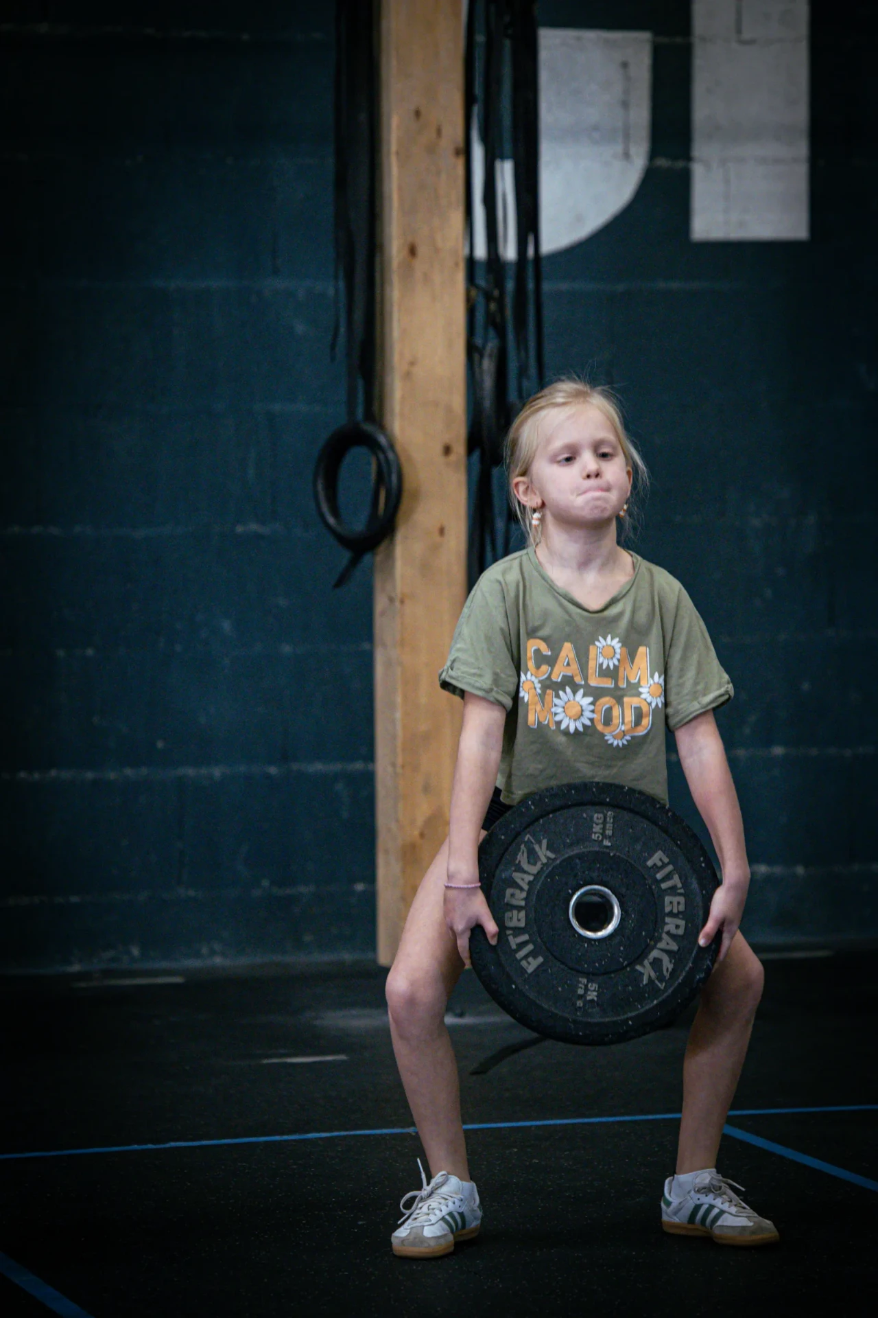 Jeune fille réalisant un squat avec un disque en cours de CrossFit Kids à Saint-Étienne