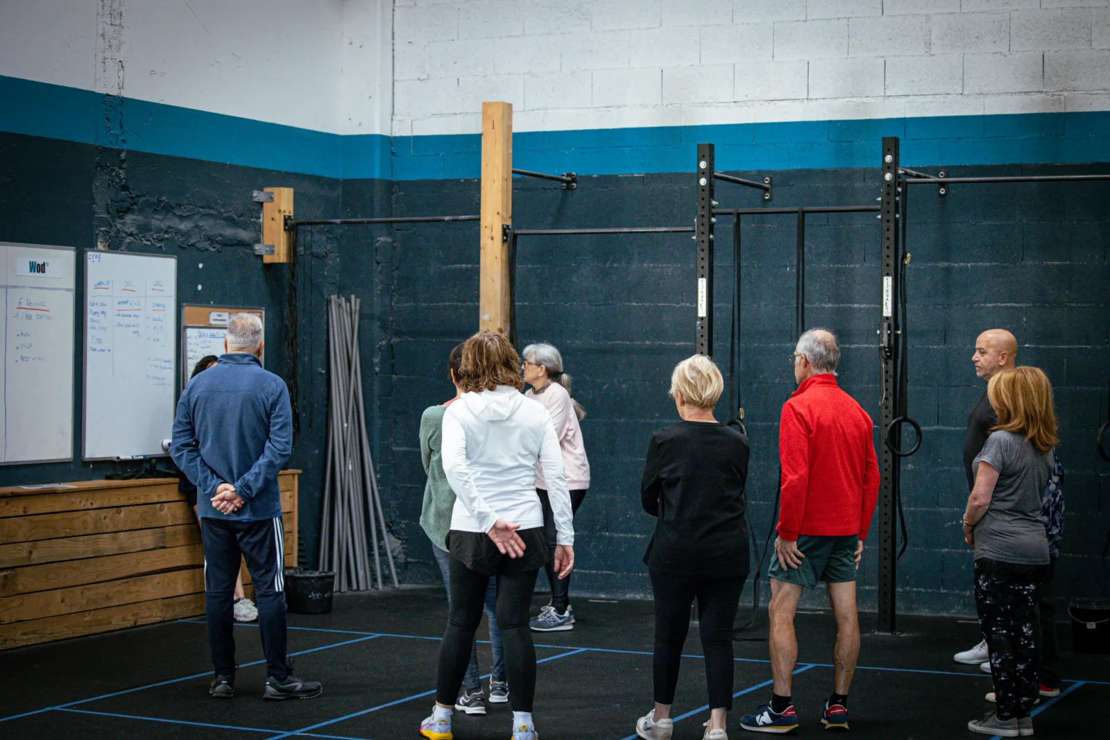 Groupe de seniors écoutant les consignes devant le tableau du WOD à CrossFit Blue Bird