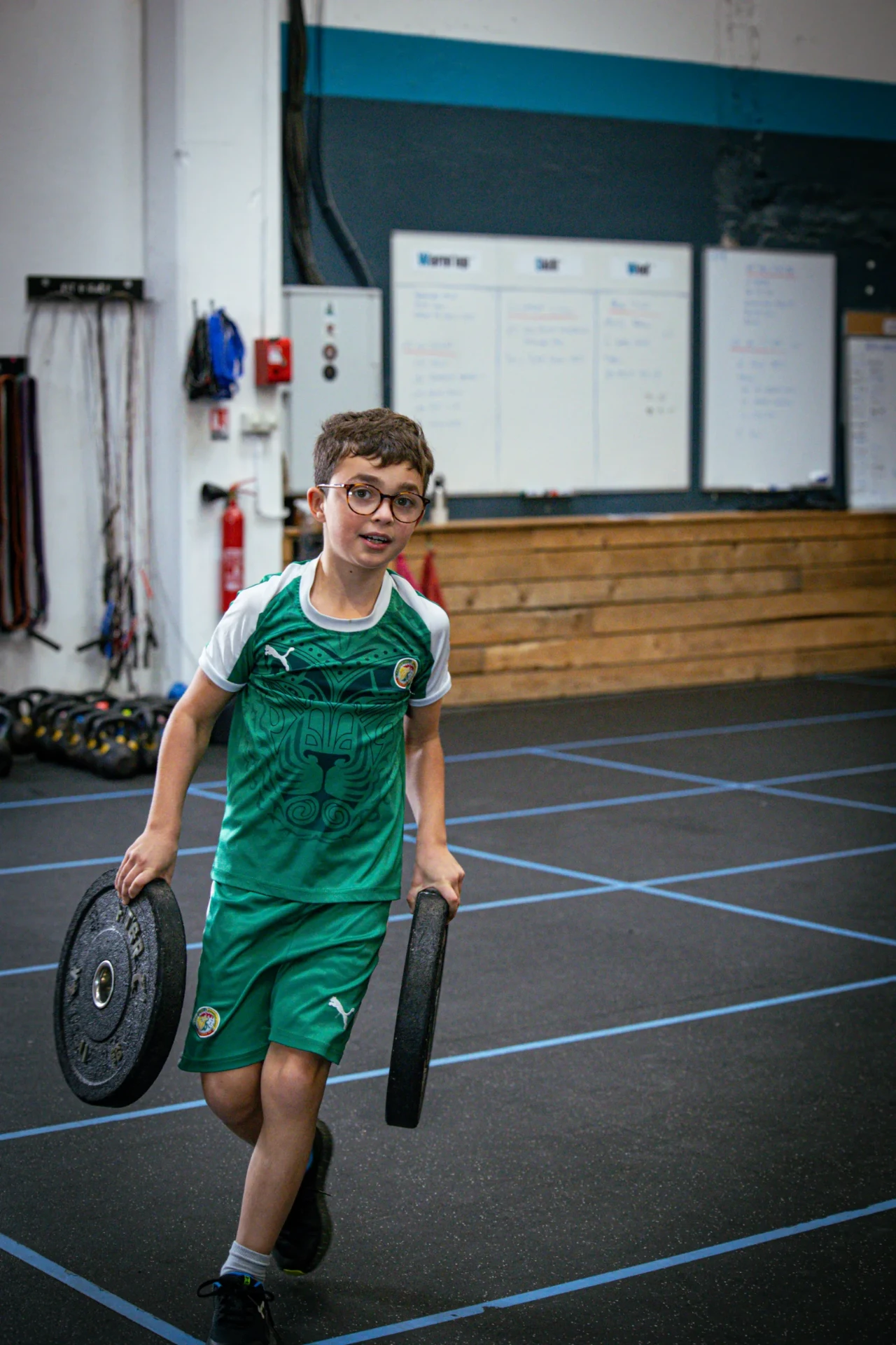 Enfant portant deux disques pendant le WOD du cours de CrossFit pour enfant